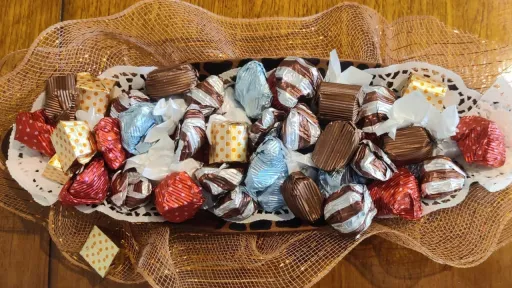 Assorted chocolates on a white decorative platter over brown mesh.