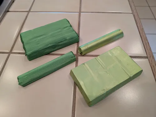 Four pieces of green chocolates on a light tiled surface.