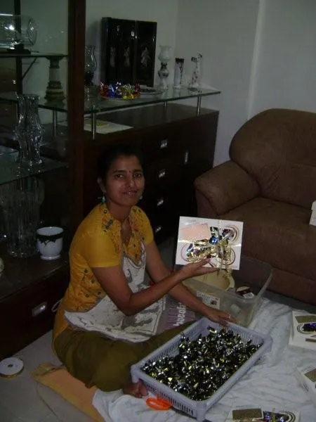 Smiling Deepa on floor holding chocolates, surrounded by more chocolates in a tray.